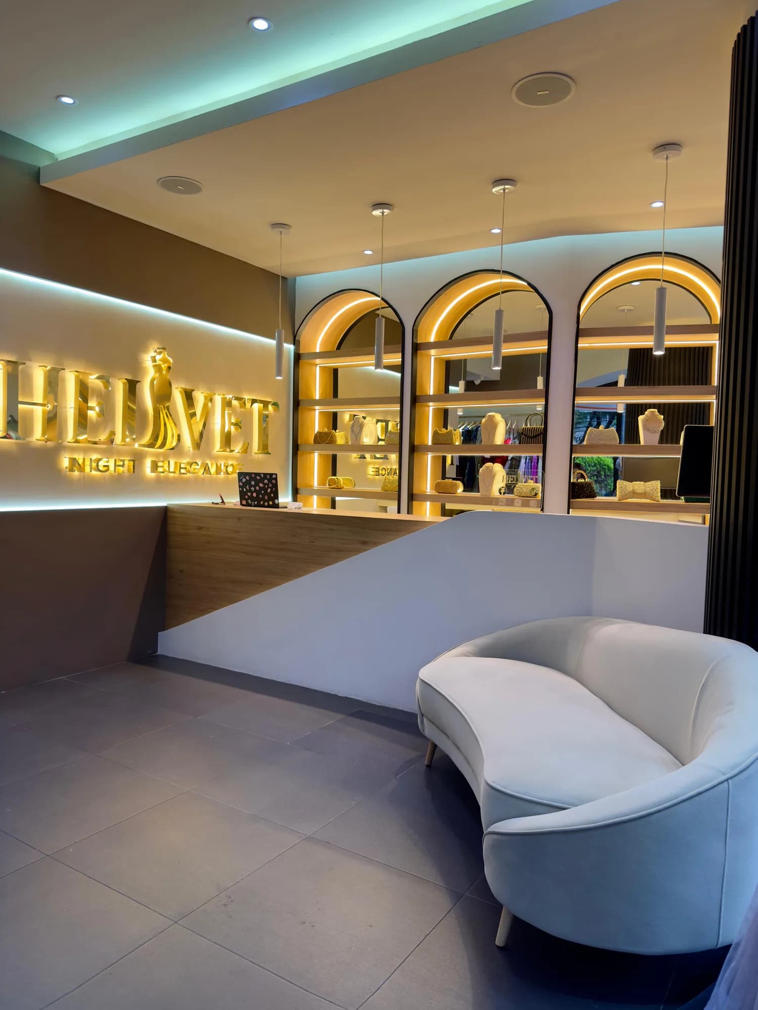 Recepción de Helvet con el logotipo iluminado, vitrinas de accesorios y un sofá de espera